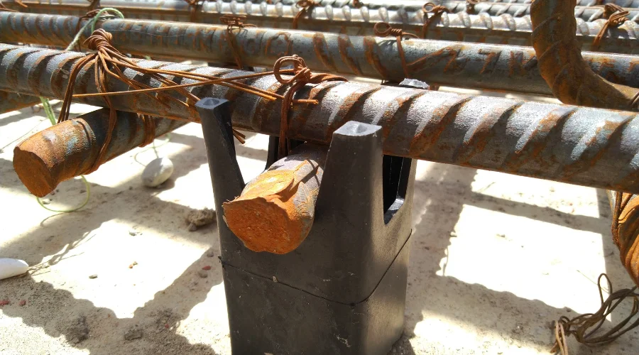Raft Foundation construction : Construction workers assembling steel reinforcement for a raft foundation at a large building site with excavation and scaffolding structures.